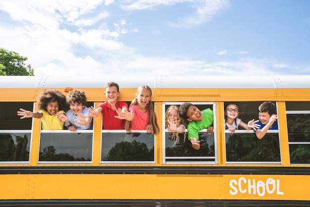 Groupe de jeunes élèves fréquentant l'école primaire sur un autobus scolaire jaune - Les enfants de l'école primaire s'amusent