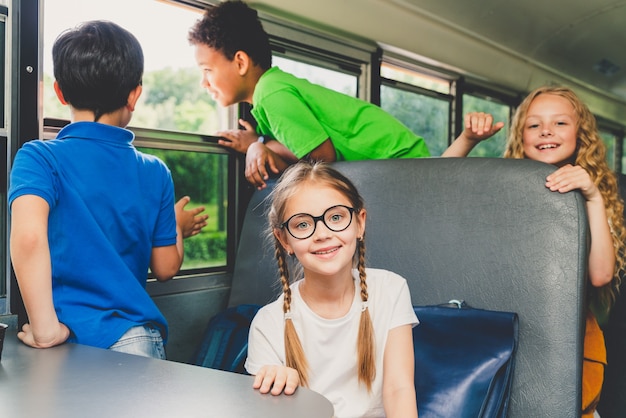 Groupe de jeunes élèves fréquentant l'école primaire sur un autobus scolaire jaune - Les enfants de l'école primaire s'amusent