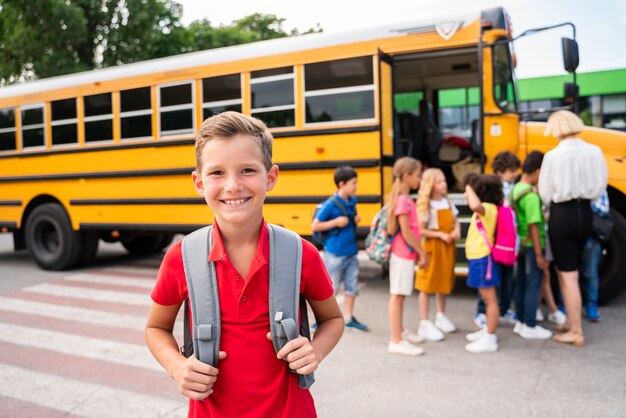 Groupe de jeunes élèves fréquentant l'école primaire sur un autobus scolaire jaune - Les enfants de l'école primaire s'amusent