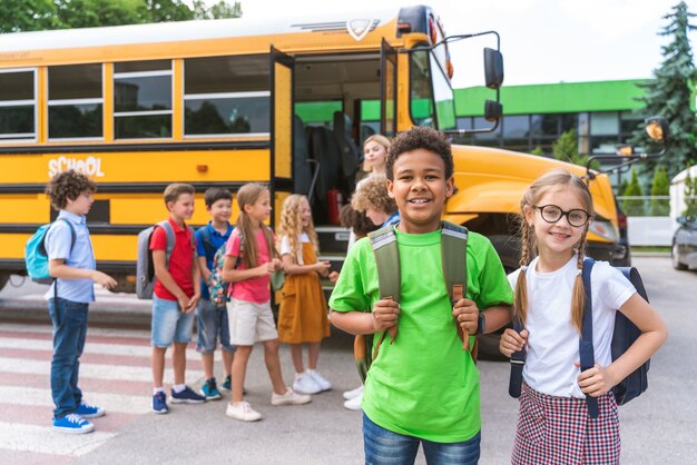 Photo groupe de jeunes élèves fréquentant l'école primaire sur un autobus scolaire jaune - les enfants de l'école primaire s'amusent