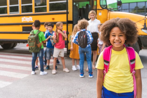 Groupe de jeunes élèves fréquentant l'école primaire sur un autobus scolaire jaune - Les enfants de l'école primaire s'amusent