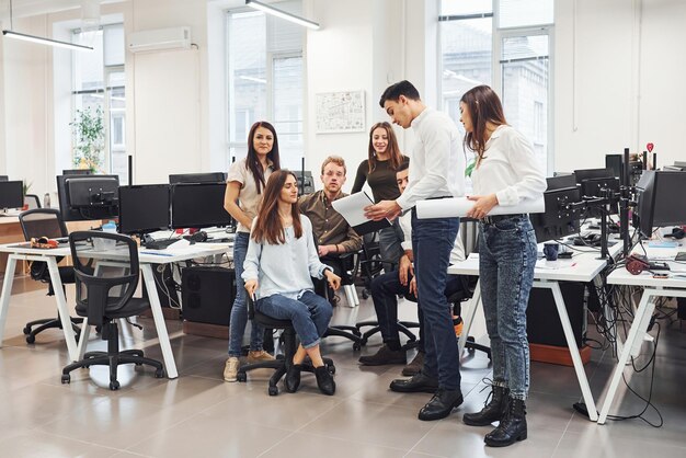 Groupe de jeunes employés parlant et travaillant sur un nouveau projet au bureau.