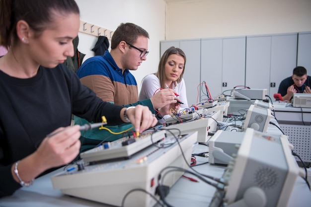 Groupe de jeunes étudiants faisant de la pratique professionnelle technique avec un enseignant dans la salle de classe électronique, concept d'éducation et de technologie