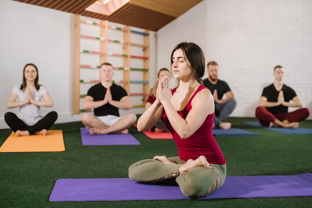 Un groupe de jeunes faisant des exercices de joga à l'intérieur au gymnase