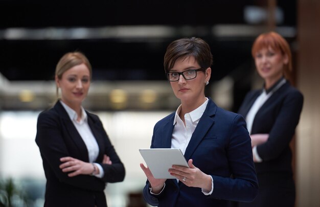 groupe de jeunes femmes d'affaires, équipe debout dans un bureau moderne et lumineux et travaillant sur une tablette