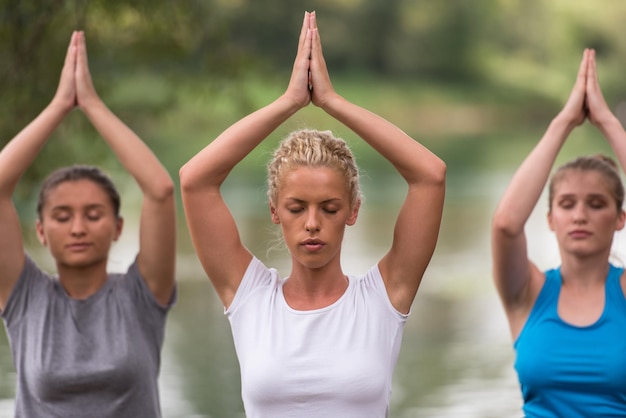 groupe de jeunes femmes en bonne santé se relaxant en méditant et en faisant des exercices de yoga dans la belle nature au bord de la rivière