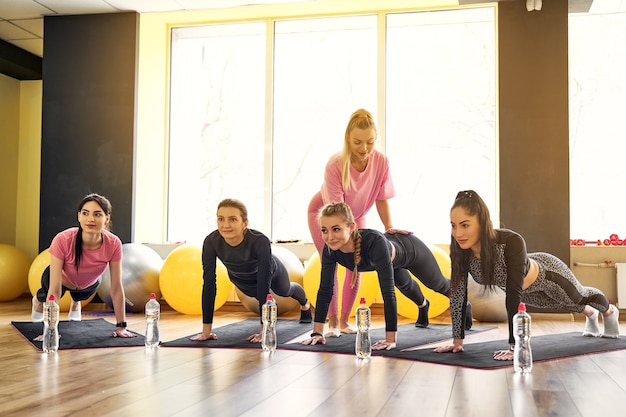 Groupe de jeunes femmes faisant planche ensemble dans une salle de sport