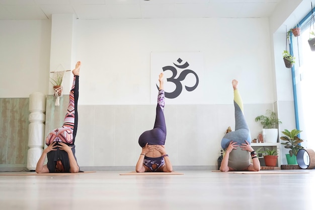 Groupe de jeunes femmes sportives pratiquant le yoga qui s'étend dans l'exercice Halasana Pose de charrue travaillant