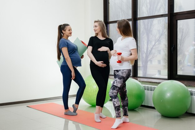 Un groupe de jeunes filles enceintes fait du yoga et socialise à l'intérieur. Mode de vie sain