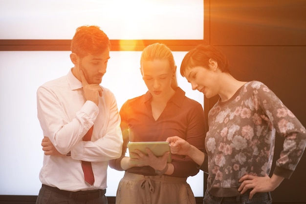 groupe de jeunes gens d'affaires en démarrage, remue-méninges et travail sur ordinateur tablette sunflare et lever de soleil en arrière-plan