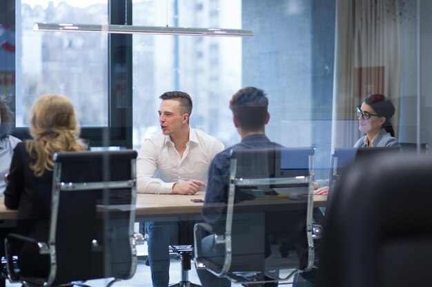 Groupe d&#39;un jeunes gens d&#39;affaires discutant de plan d&#39;affaires au bâtiment moderne de bureaux de démarrage