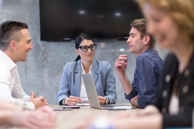 Groupe d&#39;un jeunes gens d&#39;affaires discutant de plan d&#39;affaires au bâtiment moderne de bureaux de démarrage