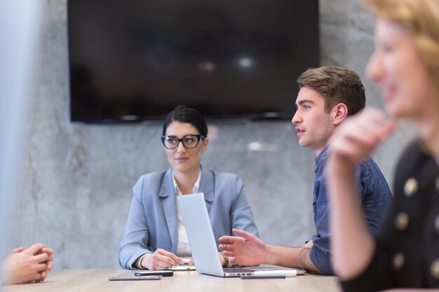 Groupe d&#39;un jeunes gens d&#39;affaires discutant de plan d&#39;affaires au bâtiment moderne de bureaux de démarrage