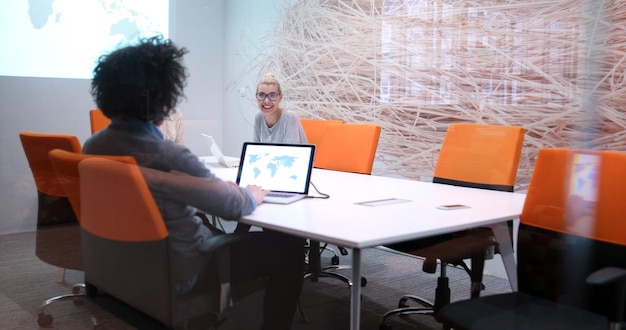 Groupe d&#39;un jeunes gens d&#39;affaires discutant de plan d&#39;affaires au bâtiment moderne de bureaux de démarrage