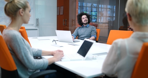 Groupe d&#39;un jeunes gens d&#39;affaires discutant de plan d&#39;affaires au bâtiment moderne de bureaux de démarrage