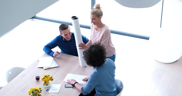 Groupe d&#39;un jeunes gens d&#39;affaires discutant de plan d&#39;affaires au bâtiment moderne de bureaux de démarrage