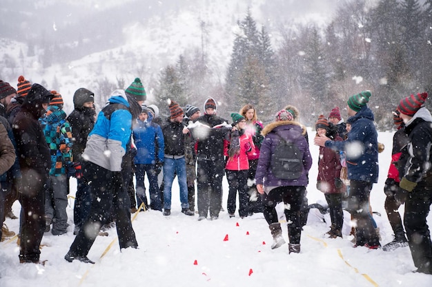 groupe de jeunes gens d'affaires heureux ayant une compétition de jeux les yeux bandés tout en profitant d'une journée d'hiver enneigée avec des flocons de neige autour d'eux lors d'un team building dans la forêt de montagne