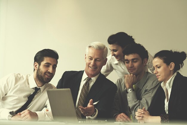 Groupe de jeunes gens d'affaires lors d'une réunion au bureau de démarrage moderne avec un cadre supérieur. Chef d'équipe à la recherche de présentation et de résultats sur tablette et ordinateur portable.