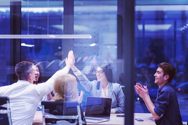 Groupe de jeunes gens d'affaires qui ont l'air heureux tout en célébrant le succès sur leur lieu de travail dans un bureau de démarrage