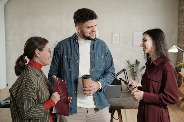 Groupe de jeunes gens d'affaires se parlant tout en se tenant au bureau