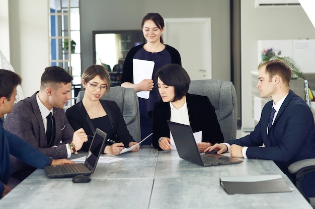 Groupe de jeunes gens d'affaires se réunissant au bureau pour discuter ensemble d'une idée importante