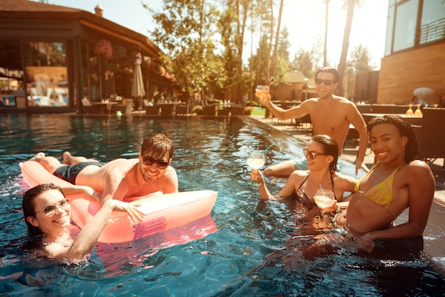 Groupe de jeunes gens heureux nageant dans la piscine