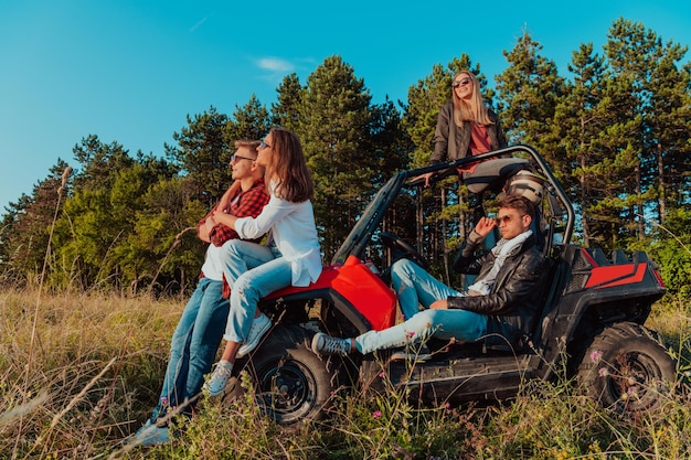 Photo groupe de jeunes gens heureux profitant d'une belle journée ensoleillée tout en conduisant une voiture buggy hors route sur la nature de la montagne.