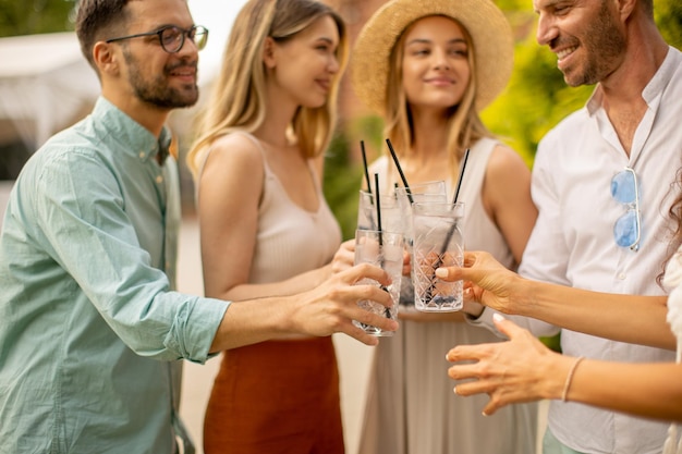 Groupe de jeunes heureux acclamant avec de la limonade fraîche dans le jardin