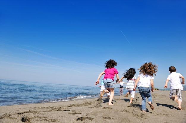 groupe de jeunes heureux s'amuser courir et sauter sur la plage belle plage de sable