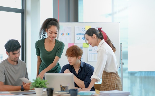 Groupe de jeunes hommes d'affaires asiatiques en vêtements décontractés intelligents travaillant ensemble dans un bureau créatif à l'aide d'un ordinateur portable