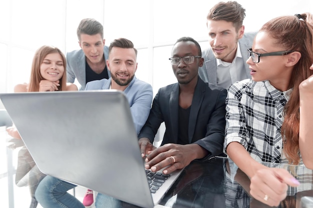 Groupe de jeunes hommes d'affaires confiants analysant des données à l'aide d'un ordinateur et souriant tout en travaillant au bureau