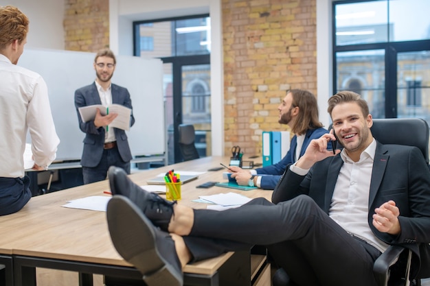 Groupe De Jeunes Hommes Joyeux En Costumes Bavardant Au Bureau Après Présentation Dans Une Atmosphère Calme