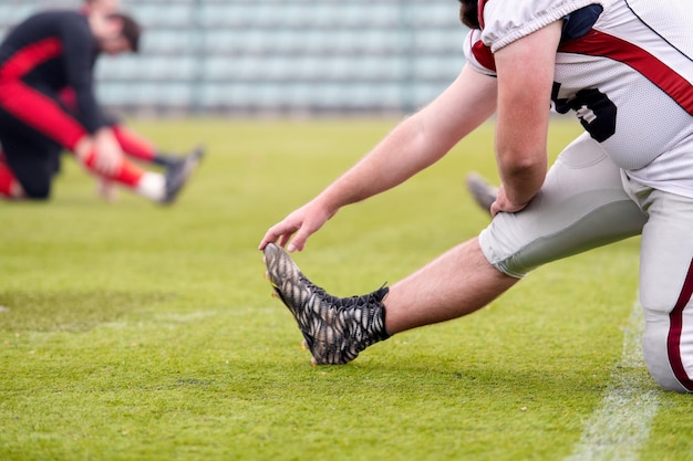 groupe de jeunes joueurs de football américain s'échauffant et s'étirant ensemble avant un entraînement sur le terrain