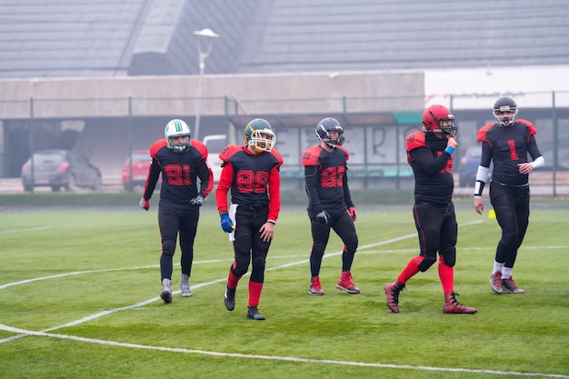 Photo groupe de jeunes joueurs de football américains confiants traversant le terrain du stade après un dur match d'entraînement