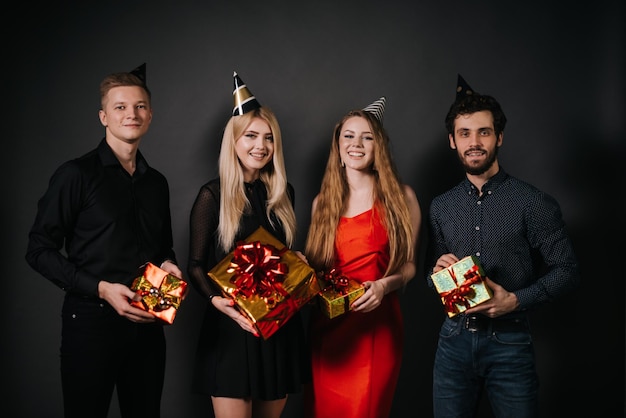 Groupe de jeunes joyeux tenant des coffrets cadeaux lumineux dans les mains