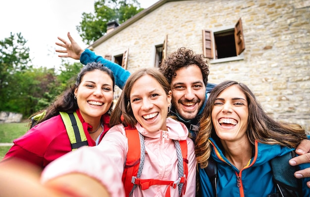 Photo groupe de jeunes prenant un selfie lors d'une excursion de trekking par un chalet de campagne concept de style de vie sportif avec des amis du millénaire heureux s'amusant ensemble lors d'une expérience de camping filtre nuageux lumineux