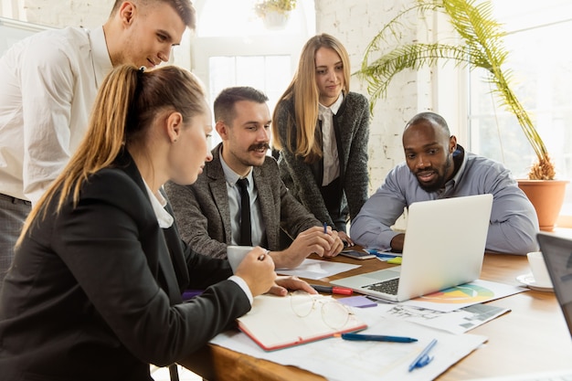 Groupe de jeunes professionnels ayant une réunion. Divers groupes de collègues discutent des nouvelles décisions, des plans futurs et de la stratégie. Réunion et lieu de travail créatifs, affaires, finances, travail d'équipe.