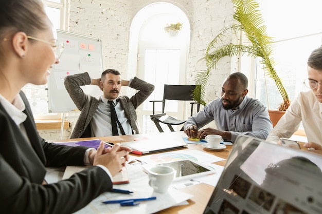 Groupe de jeunes professionnels ayant une réunion. Divers groupes de collègues discutent des nouvelles décisions, des plans futurs et de la stratégie. Réunion et lieu de travail créatifs, affaires, finances, travail d'équipe.