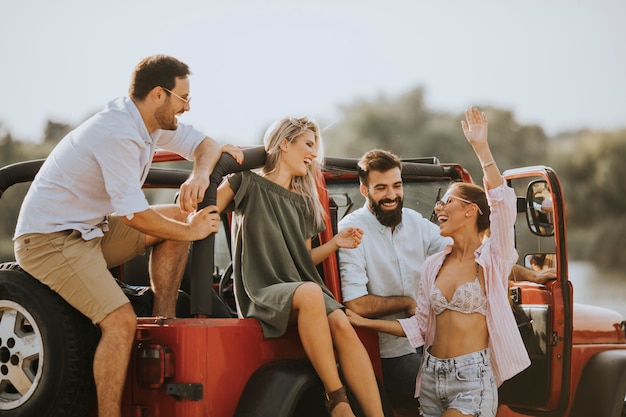 Groupe de jeunes s'amuser en voiture en plein air à une chaude journée d'été