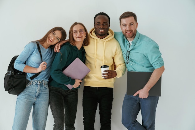 Un groupe de jeunes souriants se tiennent sur un fond blanc.