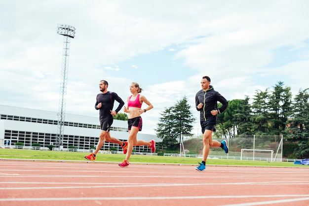 Groupe de jeunes sportifs courant sur le terrain d'athlétisme