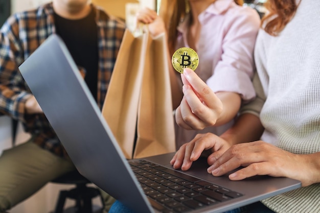 Groupe de jeunes utilisant un ordinateur portable et des bitcoins pour faire des achats en ligne ensemble