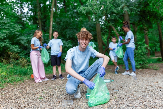 Groupe de jeunes volontaires adultes avec des sacs à ordures nettoyant le concept de préservation et d'écologie de l'environnement du parc de la ville