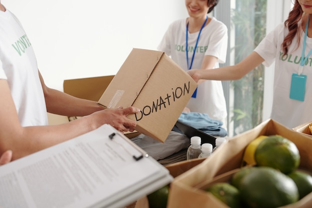 Groupe de jeunes volontaires travaillant au centre de dons, ils emballent des produits d'épicerie et des vêtements pour les personnes dans le besoin