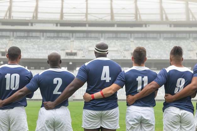 Un groupe de joueurs de rugby masculins divers prenant l'engagement ensemble dans le stade