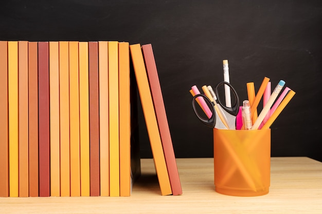 Groupe de livres et de crayons sur table en bois et tableau noir à l'arrière-plan. Espace de copie