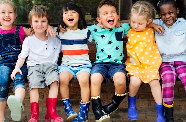 Groupe de maternelle enfants amis bras autour assis et sourire