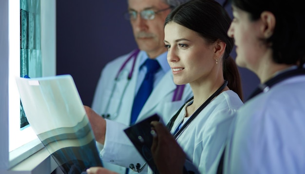 Groupe de médecins examinant des radiographies dans une clinique pensant à un diagnostic