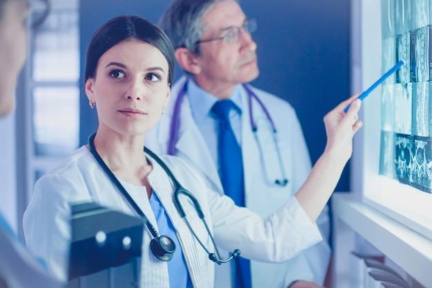 Groupe de médecins examinant les rayons X dans une clinique, pensant à un diagnostic