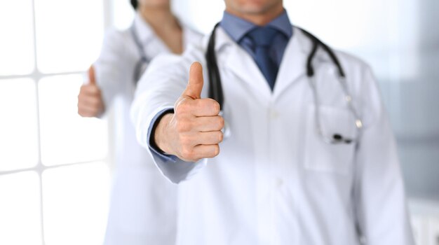 Un groupe de médecins joyeux souriant à la caméra, le pouce en l'air. Un service médical parfait dans la clinique. Un avenir heureux dans la médecine et les soins de santé.